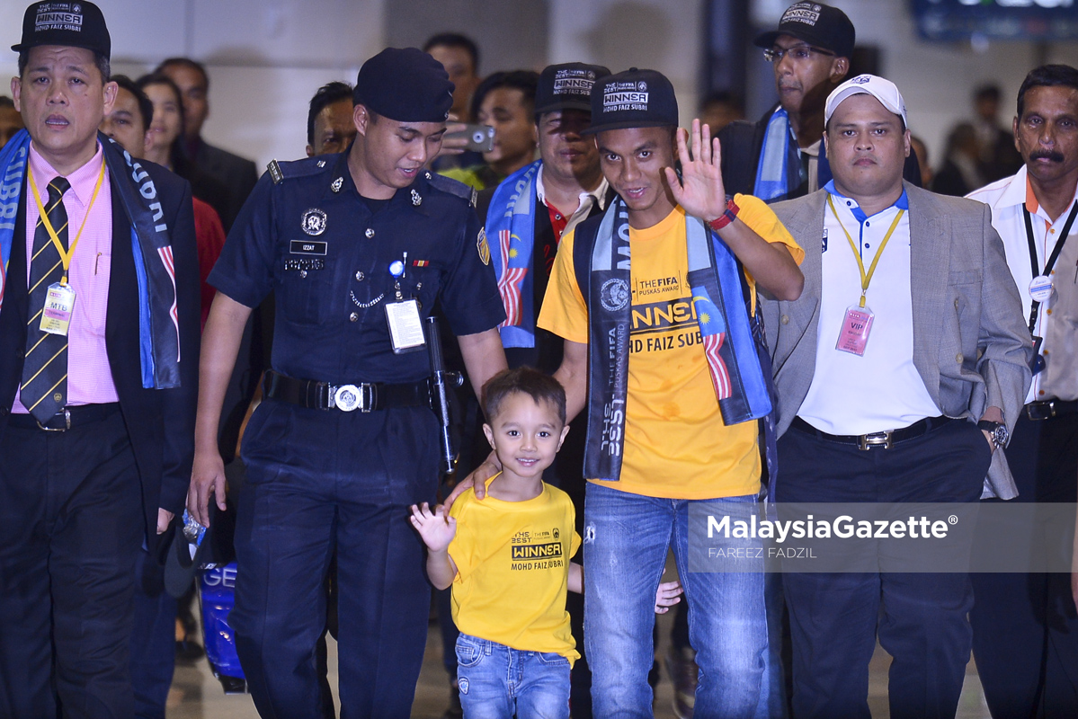 Faiz Subri (tengah) melambai sambil ditemani anaknya Akif Fayyadh selepas memenangi Anugerah FIFA PUSKAS 2016 ketika tiba di Lapangan Terbang Antarabangsa Kuala Lumpur (KLIA), Sepang. foto FAREEZ FADZIL, 11 JANUARI 2017
