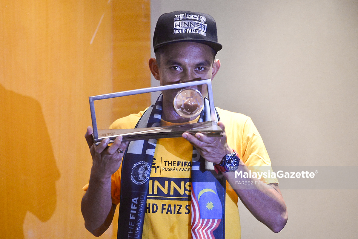 Faiz Subri mencium trofi kemenangan Anugerah FIFA PUSKAS 2016 pada sesi sidang media ketika tiba di Lapangan Terbang Antarabangsa Kuala Lumpur (KLIA), Sepang. foto FAREEZ FADZIL, 11 JANUARY 2017