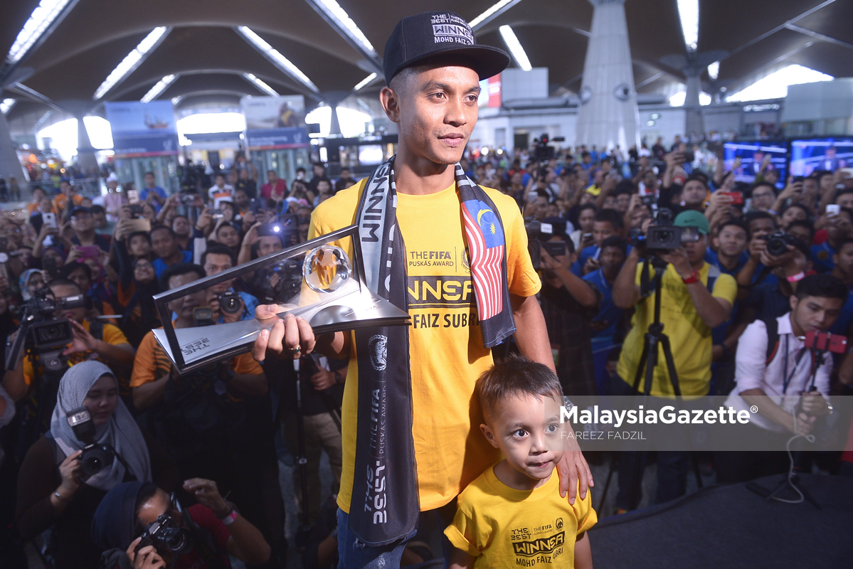 Faiz Subri ditemani anaknya Akif Fayyadh menunjukkan Anugerah FIFA PUSKAS 2016 yang dimenanginya ketika tiba di Lapangan Terbang Antarabangsa Kuala Lumpur (KLIA), Sepang. foto FAREEZ FADZIL, 11 JANUARI 2017