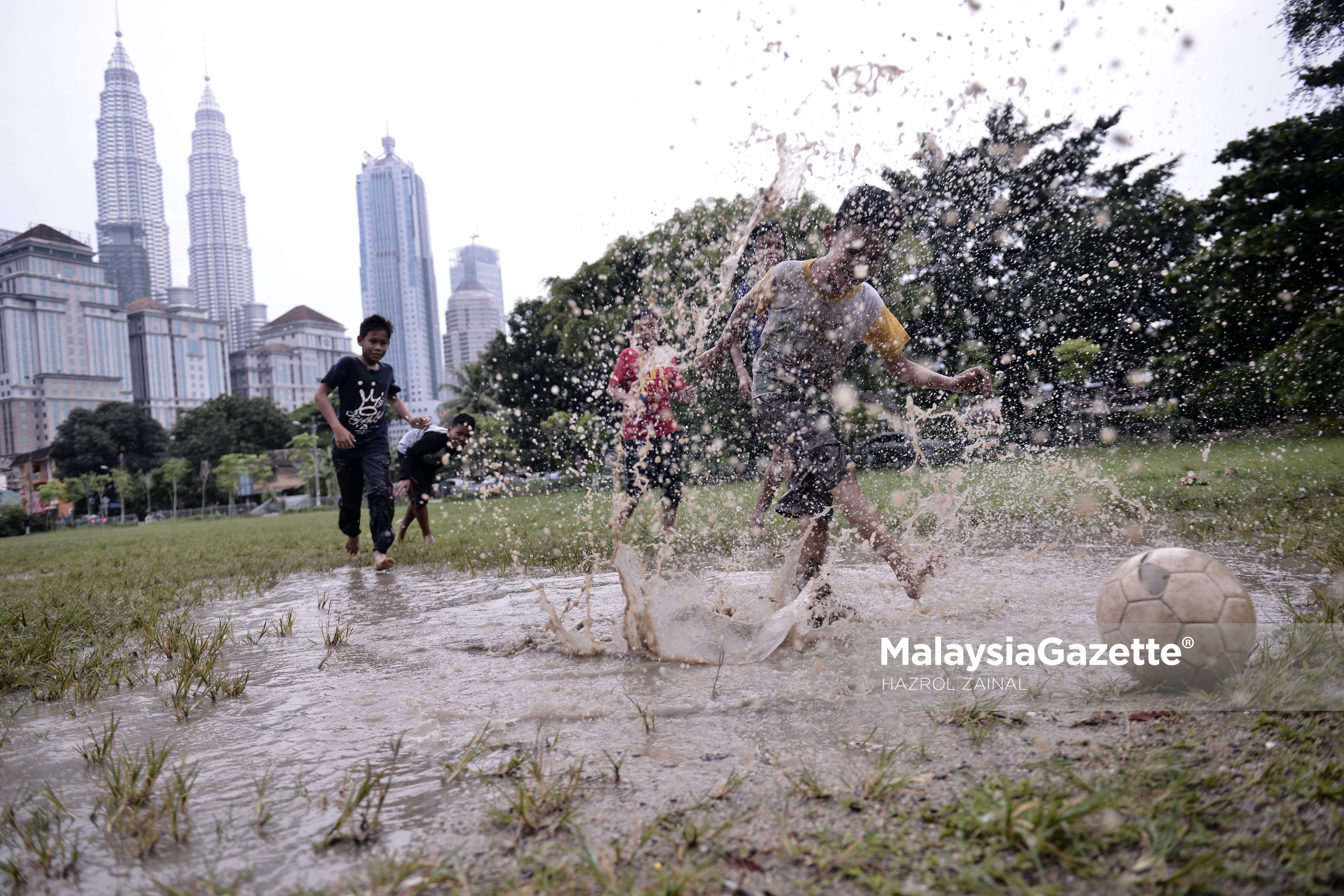 Sekumpulan kanak-kanak riang bermain bola sepak di padang yang berlecak berikutan hujan lebat pada hari terakhir cuti persekolahan ketika tinjauan lensa Malaysia Gazette di sekitar Kuala Lumpur. foto MOHD HAZROL ZAINAL, 26 MAC 2017.