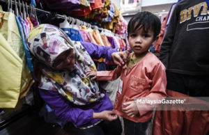 Ibu, Nor Hasimah Mohd Rahim, 38 (kiri) memakaikan baju melayu kepada anaknya, Muhammad Iman Mohd Zaki, 2 (kanan) pada Program Shopping Raya Bersama Anak-Anak Yatim dan Miskin 2018 Anjuran Yayasan PEKEMA di Mydin Mall Subang Jaya, Selangor. foto SYAFIQ AMBAK, 09 JUN 2018