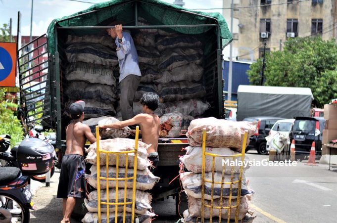 Tiga orang lelaki mengeluarkan beberapa guni beras dari sebuah lori ketika tinjauan lensa MalaysiaGazette di sekitar kawasan Chow Kit, Kuala Lumpur. foto AFFAN FAUZI, 27 SEPTEMBER 2017