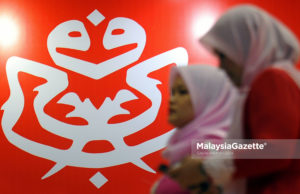 Dua perwakilan Pergerakan Puteri UMNO dilihat melintasi dinding yang dihiasi logo parti UMNO ketika tinjauan lensa Malaysia Gazette sempena Perhimpunan Agung UMNO 2017 di Pusat Dagangan Dunia Putra (PWTC), Kuala Lumpur. foto SAFWAN MANSOR, 07 DISEMBER 2017