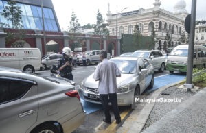 Seorang Penguatkuasa DBKL mengeluarkan saman terhadap seorang pemandu atas kesalahan meletakkan kenderaan di laluan basikal ketika tinjauan lensa Malaysia Gazette di sekitar Kuala Lumpur. foto AFFAN FAUZI, 1 FEBRUARI 2018