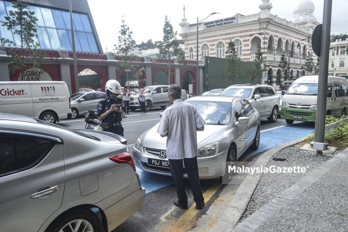 Seorang Penguatkuasa DBKL mengeluarkan saman terhadap seorang pemandu atas kesalahan meletakkan kenderaan di laluan basikal ketika tinjauan lensa Malaysia Gazette di sekitar Kuala Lumpur. foto AFFAN FAUZI, 1 FEBRUARI 2018