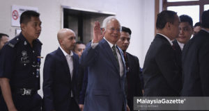 Bekas Perdana Menteri, Datuk Seri Najib Tun Razak melambaikan kepada para media sambil diiringi pegawai polis semasa tiba di mahkamah bagi sebutan kes melibatkan rasuah di Mahkamah Sesyen, Kompleks Mahkamah Jalan Duta, Kuala Lumpur. foto SYAFIQ AMBAK, 08 OGOS 2018