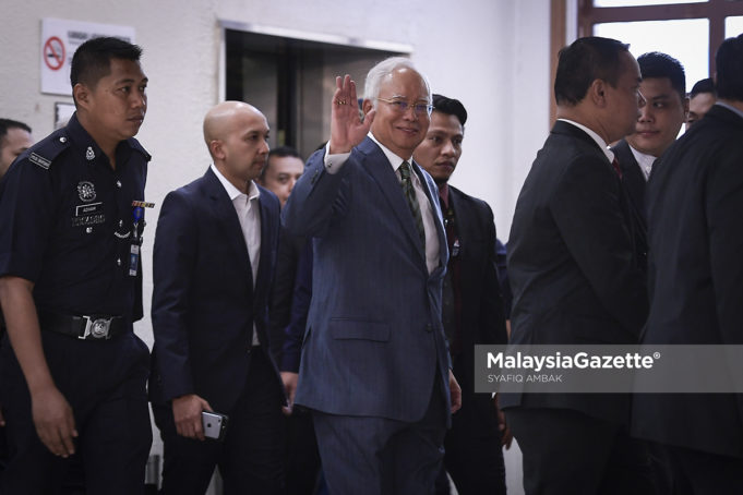 Bekas Perdana Menteri, Datuk Seri Najib Tun Razak melambaikan kepada para media sambil diiringi pegawai polis semasa tiba di mahkamah bagi sebutan kes melibatkan rasuah di Mahkamah Sesyen, Kompleks Mahkamah Jalan Duta, Kuala Lumpur. foto SYAFIQ AMBAK, 08 OGOS 2018