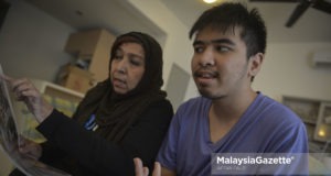 Ibu kepada pesakit autisme, Hasnah Abdul Rahman melihat keratan akhbar sambil ditemani oleh anaknya yang jugak pesakit autisme, Ahmad Ziqri Morshidi di Villa Orkid, Bukit Prima Pelangi, Kuala Lumpur. foto AFFAN FAUZI, 10 APRIL 2018