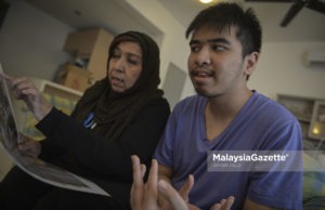 Ibu kepada pesakit autisme, Hasnah Abdul Rahman melihat keratan akhbar sambil ditemani oleh anaknya yang jugak pesakit autisme, Ahmad Ziqri Morshidi di Villa Orkid, Bukit Prima Pelangi, Kuala Lumpur. foto AFFAN FAUZI, 10 APRIL 2018