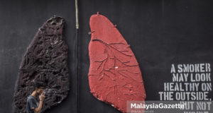 Seorang perokok sedang melintasi lukisan pada dinding yang memaparkan mengenai perbezaan warna paru-paru individu yang merokok dan tidak merokok ketika tinjauan lensa MalaysiaGazette di Shah Alam, Selangor. foto IMRAN FAKHRI, 1 FEBRUARI 2018