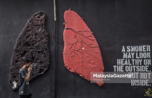Seorang perokok sedang melintasi lukisan pada dinding yang memaparkan mengenai perbezaan warna paru-paru individu yang merokok dan tidak merokok ketika tinjauan lensa MalaysiaGazette di Shah Alam, Selangor. foto IMRAN FAKHRI, 1 FEBRUARI 2018