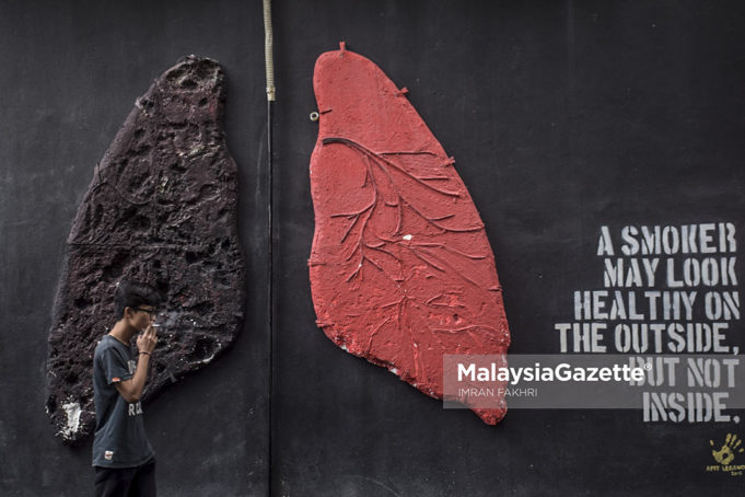 Seorang perokok sedang melintasi lukisan pada dinding yang memaparkan mengenai perbezaan warna paru-paru individu yang merokok dan tidak merokok ketika tinjauan lensa MalaysiaGazette di Shah Alam, Selangor. foto IMRAN FAKHRI, 1 FEBRUARI 2018