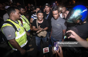 Polis surai sekumpulan lelaki berkumpul di kawasan kuil