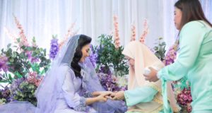 Rokkiah Md Noor menyarungkan cincin tanda pertunangan ke jari Fasha sambil disaksikan oleh ayah Aidil, Abdul Aziz Ishak.