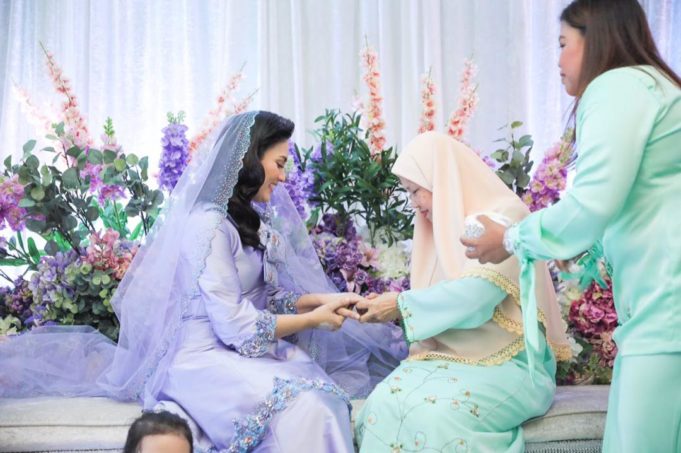 Rokkiah Md Noor menyarungkan cincin tanda pertunangan ke jari Fasha sambil disaksikan oleh ayah Aidil, Abdul Aziz Ishak.