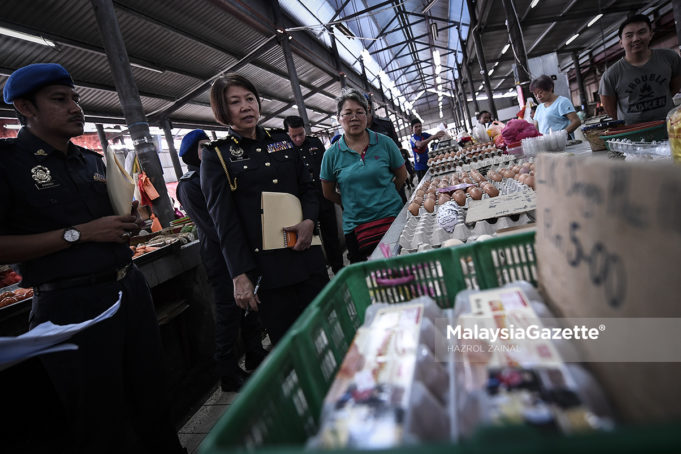 Ketua Pegawai Penguatkuasa KPDNKK WPKL, Low Swee Hon (dua kiri) meneliti jenis telur yang dijual peniaga semasa membuat pemantauan dan pemeriksaan harga barang di Pasar Jalan Klang Lama, Kuala Lumpur. foto HAZROL ZAINAL, 30 MEI 2018.