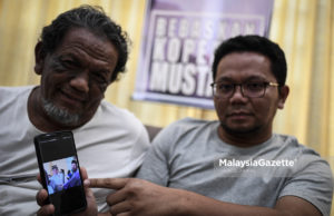 Mahathir Abdul Rahman (kanan) bersama ayahnya, Abdul Rahman Abd Hamid (kiri) menunjukkan gambar kenangan adiknya yang seorang mekanik polis, Mustaza Abdul Rahman dipenjarakan bawah tahanan Sosma di kediamannya di Taman Setapak Indah, Kuala Lumpur. foto HAZROL ZAINAL, 18 MEI 2019.