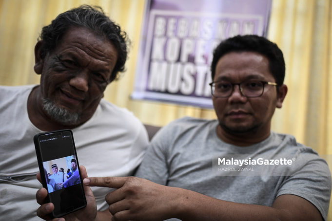 Mahathir Abdul Rahman (kanan) bersama ayahnya, Abdul Rahman Abd Hamid (kiri) menunjukkan gambar kenangan adiknya yang seorang mekanik polis, Mustaza Abdul Rahman dipenjarakan bawah tahanan Sosma di kediamannya di Taman Setapak Indah, Kuala Lumpur. foto HAZROL ZAINAL, 18 MEI 2019.