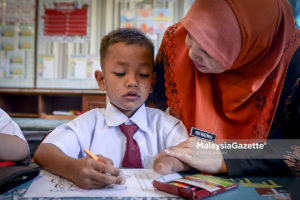 Murid tahun satu yang juga merupakan seorang Orang Kurang Upaya (OKU), Muhamad Asil Firas, 7, ditemeni seorang guru ketika pembelajaran pada hari pertama sesi persekolahan bagi sesi 2020 semasa tinjauan lensa Malaysia Gazette di Sekolah Kebangsaan Setiawangsa, Kuala Lumpur. foto SYAFIQ AMBAK, 02 JANUARI 2020