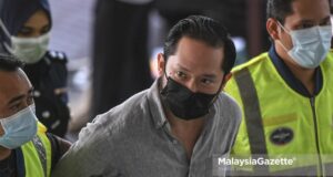The founder of Sugarbook mobile application, Chan Eu Boon is escorted by the police to be charged at the Shah Alam Courts Courts Complex. PIX: SYAFIQ AMBAK / MalaysiaGazette / 24 FEBRUARY 2021