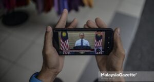 Trader, Ramli Berahim watches the special announcement by Prime Minister Tan Sri Muhyiddin on his mobile phone at Jalan Tuanku Abdul Rahman, Kuala Lumpur. PIX: AFFAN FAUZI / MalaysiaGazette /17 MARCH 2021 Pemerkasa one-off RM500 cash aid payment for B40 who lost jobs