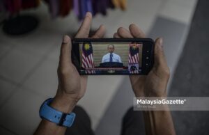 Trader, Ramli Berahim watches the special announcement by Prime Minister Tan Sri Muhyiddin on his mobile phone at Jalan Tuanku Abdul Rahman, Kuala Lumpur. PIX: AFFAN FAUZI / MalaysiaGazette /17 MARCH 2021 Pemerkasa one-off RM500 cash aid payment for B40 who lost jobs