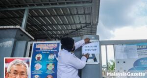 Security guard, Jamalina Mohammad Ibrahim, 38, putting up a notice on school closure at Sekolah Menengah Kebangsaan Seksyen 7, Shah Alam after the emergence of Covid-19 pandemic cluster that forced the closure of 19 schools in Selangor. PIX: MOHD ADZLAN / MalaysiaGazette / 20 APRIL 2021. Picture in frame: Associate Professor Dr Mohamad Ali Hasan.