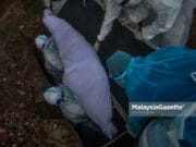 Covid-19: 15 new deaths on 12 Jan A Covid-19 body is laid to rest at the Section 21 Muslim Cemetery in Shah Alam, Selangor. PIX: MOHD ADZLAN / MalaysiaGazette / 20 MAY 2021. Petugas Kesihatan mengendalikan jenazah pesakit Covid-19 ketika tinjauan lensa Malaysia Gazette di Tanah Perkuburan Islam Seksyen 21, Shah Alam. Foto MOHD ADZLAN, 20 MEI 2021. Covid-19 death toll deaths