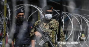 (Picture for representional purposes only). The police and members from the Malaysian Armed Forces (MAF) on guard at the main entrance of Kampung Limau People's Housing Project (PPR) in Kuala Lumpur following the Enhanced Movement Control Order (EMCO) to curb the spread of Covid-19 at the area. PIX: SYAFIQ AMBAK / MalaysiaGazette / 23 MAY 2021 full lockdown Malaysia 1 - 14 June 2021 The government has decided to implement a nationwide total lockdown by fully closing the social and economic sectors for a period of 14 days from 1 until 14 June 2021.