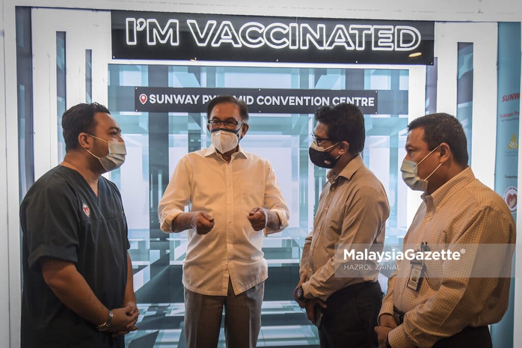 Presiden PKR, Datuk Seri Anwar Ibrahim mengatakan sesuatu dengan petugas kesihatan ketika memantau pelaksanaan proses vaksinasi di Pusat Pemberian Vaksin (PPV) Sunway Pyramid, Selangor. Foto HAZROL ZAINAL, 28 MEI 2021.