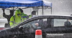 The police and Malaysian Armed Forces (MAF) inspecting the interstate travel permit in the rain at the Gombak Toll Plaza following the nationwide Movement Control Order (MCO) and interstate travel ban to curb the spread of Covid-19. PIX: SYAFIQ AMBAK / MalaysiaGazette / 16 MAY 2021.