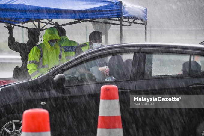 The police and Malaysian Armed Forces (MAF) inspecting the interstate travel permit in the rain at the Gombak Toll Plaza following the nationwide Movement Control Order (MCO) and interstate travel ban to curb the spread of Covid-19. PIX: SYAFIQ AMBAK / MalaysiaGazette / 16 MAY 2021.
