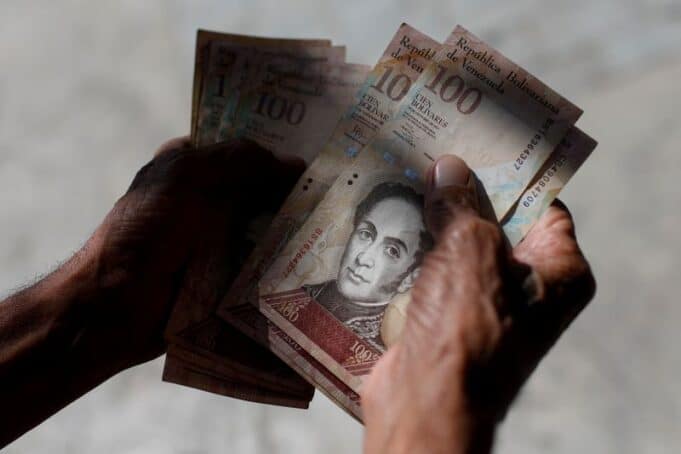 FILE PHOTO: A man counts Venezuelan bolivar notes in downtown Caracas