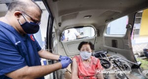 Dr. Sathia Prakash Nadarajan administering the Covid-19 vaccine to Lim Leong Moy, 89 in her car. PIX: HAFIZ SOHAIMI / MalaysiaGazette / 15 JUNE 2021 Vaccination Malaysian population