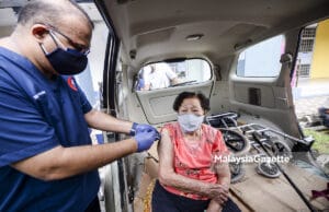 Dr. Sathia Prakash Nadarajan administering the Covid-19 vaccine to Lim Leong Moy, 89 in her car. PIX: HAFIZ SOHAIMI / MalaysiaGazette / 15 JUNE 2021 Vaccination Malaysian population