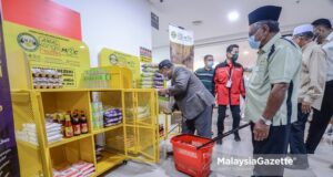 white flag campaign movement neighbours village chief Minister of Plantation Industries and Commodities, Datuk Mohd Khairuddin Aman Razali arranging essential items on the rack at Komoditi Legasi Sabasun HyperRuncit Kampung Baru in Kuala Lumpur during the Kongsi Rezeki Charity Programme by the Malaysia Rubber Council (MRC) and Yayasan Amal Malaysia.   PIX: HAFIZ SOHAIMI / MalaysiaGazette / 02 JULY 2021