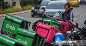 An e-hailing food delivery rider preparing to deliver food to the customer outside Sunway Putra Mall in Kuala Lumpur. PIX: MOHD ADZLAN / MalaysiaGazete / 15 APRIL 2021. commissions