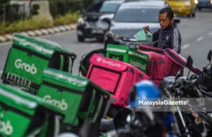 An e-hailing food delivery rider preparing to deliver food to the customer outside Sunway Putra Mall in Kuala Lumpur. PIX: MOHD ADZLAN / MalaysiaGazete / 15 APRIL 2021. commissions