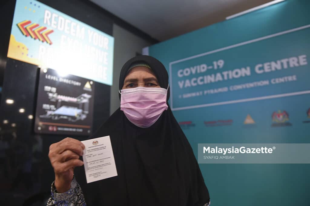 Warga emas, Zainab Salleh, 72, menunjukkan kad vaksinasi Covid-19 selepas hadir secara “walk in” untuk menerima suntikan vaksin di Pusat Pemberian Vaksin (PPV) Sunway Pyramid, Selangor. Foto SYAFIQ AMBAK, 17 JULAI 2021.