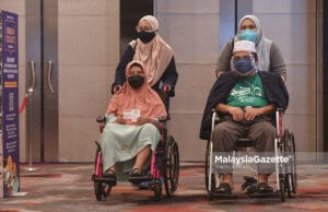 Warga emas, Siti Amun Md Amin, 85 (kiri) bersama anaknya, Abdul Razak Abdul Hamid, 60 (kanan) selepas hadir secara “walk in” untuk menerima suntikan vaksin di Pusat Pemberian Vaksin (PPV) Sunway Pyramid, Selangor. Foto SYAFIQ AMBAK, 17 JULAI 2021.