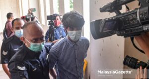 Police escort controversial film producer of ‘Babi’, Toh Han Boon, 35, to the Petaling Jaya Magistrate Court to be charged for distributing and displaying film poster without valid license. PIX: SYAFIQ AMBAK / MalaysiaGazette / 21 JULY 2021.