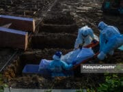 Covid-19: 9 more deaths yesterday Covid-19 death deaths Healthcare workers managing Covid-19 corpse at the Selat Klang Muslim Cemetery in Selangor. PIX: MOHD ADZLAN / MalaysiaGazette / 28 JULY 2021.