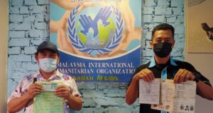 Asiri and the representative from the Malaysia International Humanitarian Organization (MHO) MHO in Sabah, showing his birth certification. Identity theft victim