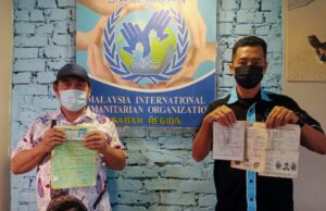 Asiri and the representative from the Malaysia International Humanitarian Organization (MHO) MHO in Sabah, showing his birth certification. Identity theft victim