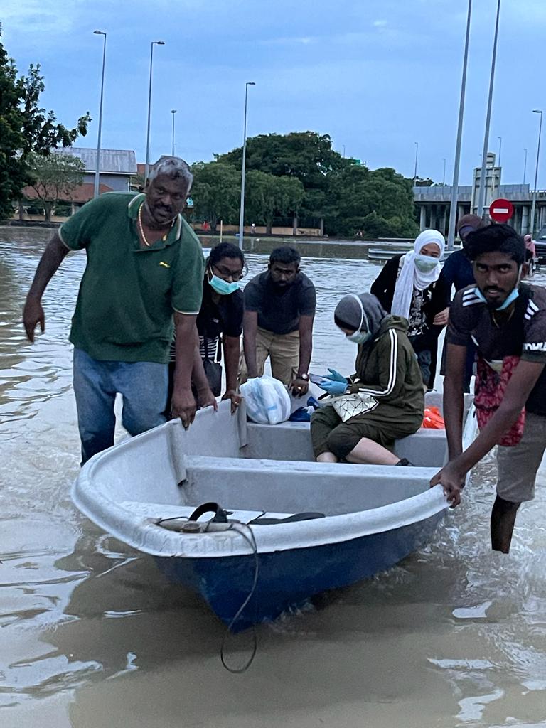   Volunteers helping to push a boat carrying a woman in Taman Sri Muda.