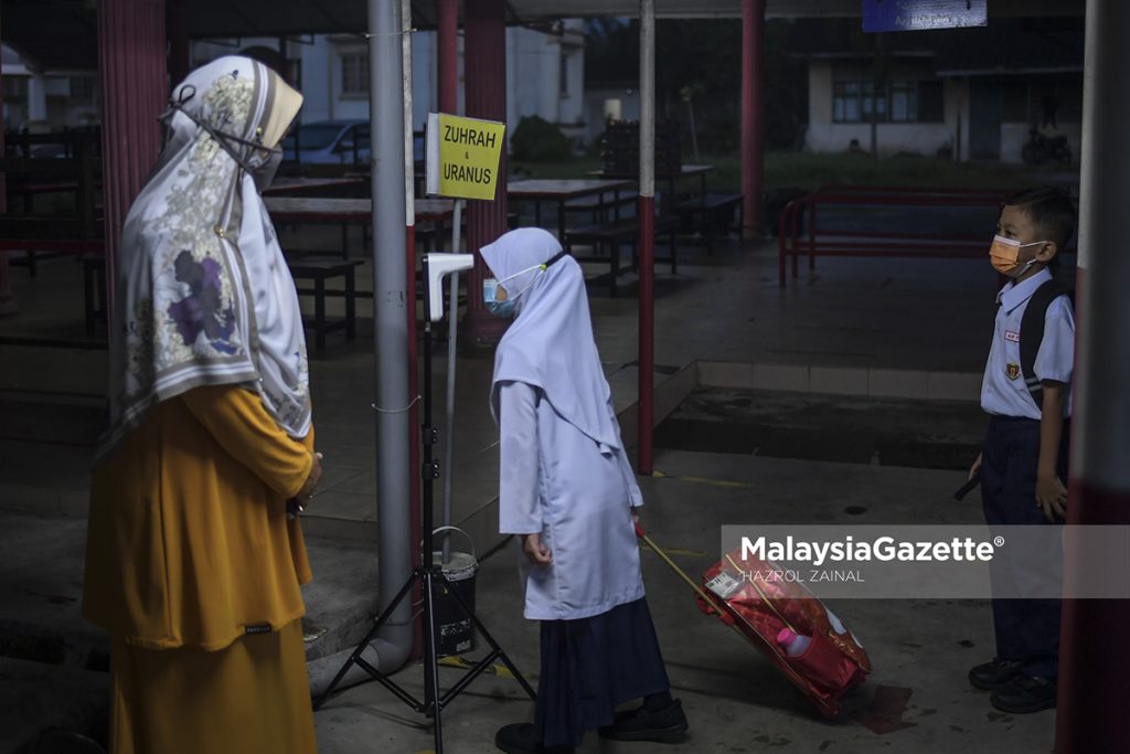 Students getting their body temperature screened while being monitored by the teacher-on-duty before entering the school for their 2021/2022 third term school session at Sekolah Kebangsaan Bukit Changgang, Banting, Selangor.     PIX: HAZROL ZAINAL / MalaysiaGazette / 10 JANUARY 2022.