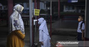 Students getting their body temperature screened while being monitored by the teacher-on-duty before entering the school for their 2021/2022 third term school session at Sekolah Kebangsaan Bukit Changgang, Banting, Selangor. PIX: HAZROL ZAINAL / MalaysiaGazette / 10 JANUARY 2022.