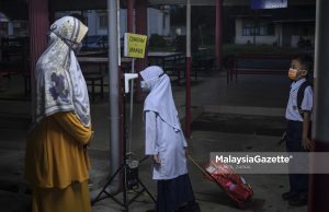 Students getting their body temperature screened while being monitored by the teacher-on-duty before entering the school for their 2021/2022 third term school session at Sekolah Kebangsaan Bukit Changgang, Banting, Selangor. PIX: HAZROL ZAINAL / MalaysiaGazette / 10 JANUARY 2022.