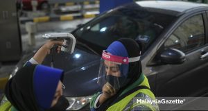 An employee from PLUS scans a vehicle with Radio Frequency Identification (RFID) tag issues using a mobile device at the Sungai Besi Toll Plaza in Kuala Lumpur. PIX: HAZROL ZAINAL / MalaysiaGazette / 17 JANUARY 2022.