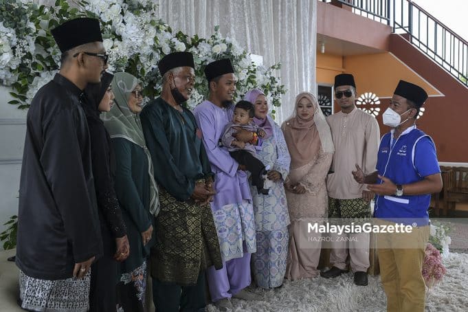 Calon Barisan Nasional (BN) N.09 Gambir, Sahrihan Jani (kanan) bergambar dengan bapa pengantin, Jazali Othman (empat kiri) serta tiga pasangan pengantin ketika berkempen di salah satu majlis perkahwin sempena Pilihan Raya Negeri (PRN) Johor di Kampung Sawah Ring, Bukit Gambir, Johor. Foto HAZROL ZAINAL, 05 MAC 2022. Foto HAZROL ZAINAL, 05 MAC 2022.